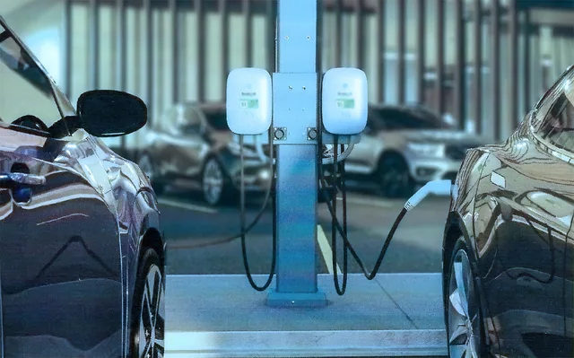 Două mașini electrice conectate la un punct de încărcare modern.