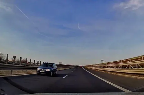 Autostradă cu trafic, mașină pe contrasens, cer senin.