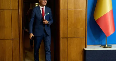 Ministrul Muncii intră în birou, având un zâmbet optimist.