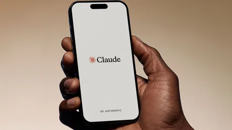 Un telefon mobil cu logo-ul Claude pe ecran, ținut de o mână.