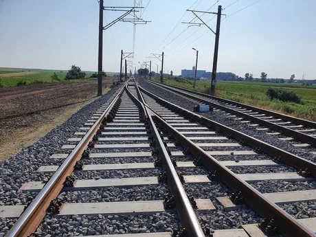 Tronson feroviar în apropierea unei zone agricole, cu linii ce se bifurcă.