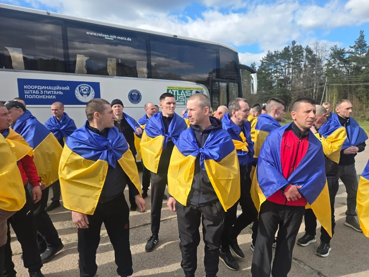 Prizonieri de război ucraineni eliberați, purtând steaguri naționale.