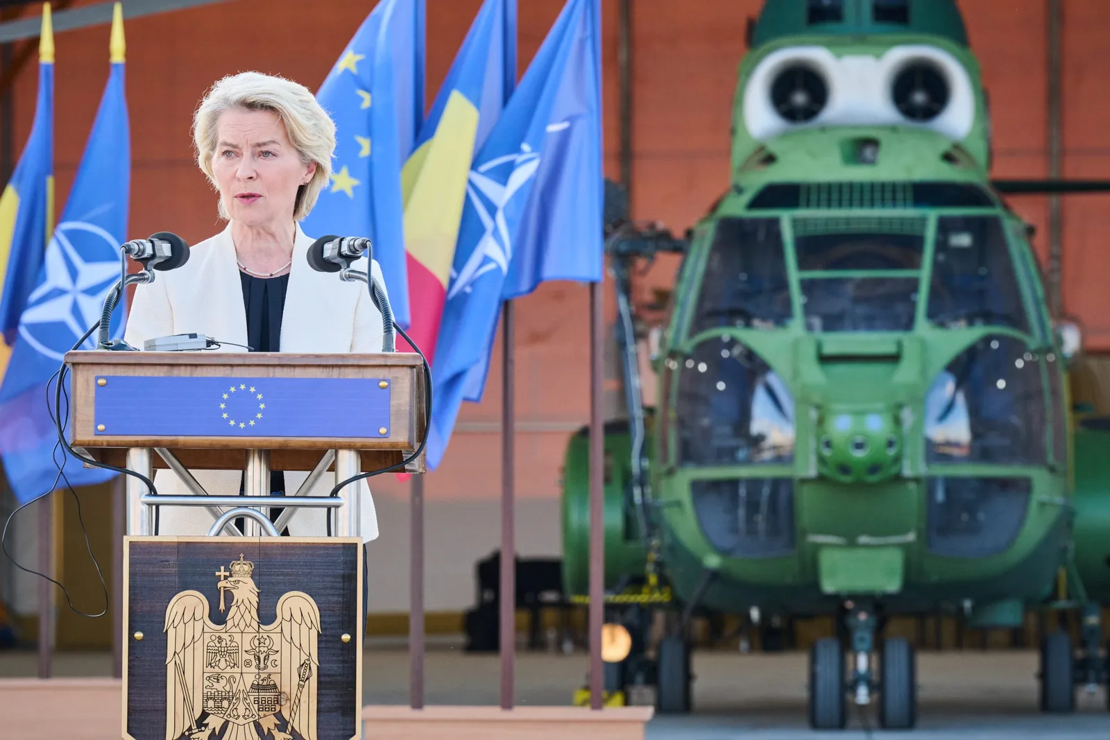 Ursula von der Leyen susține un discurs despre apărare în fața unui elicopter militar.