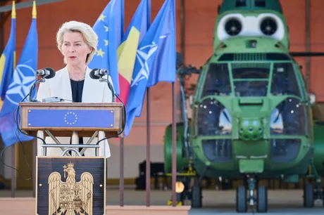 Ursula von der Leyen susține un discurs despre apărare în fața unui elicopter militar.