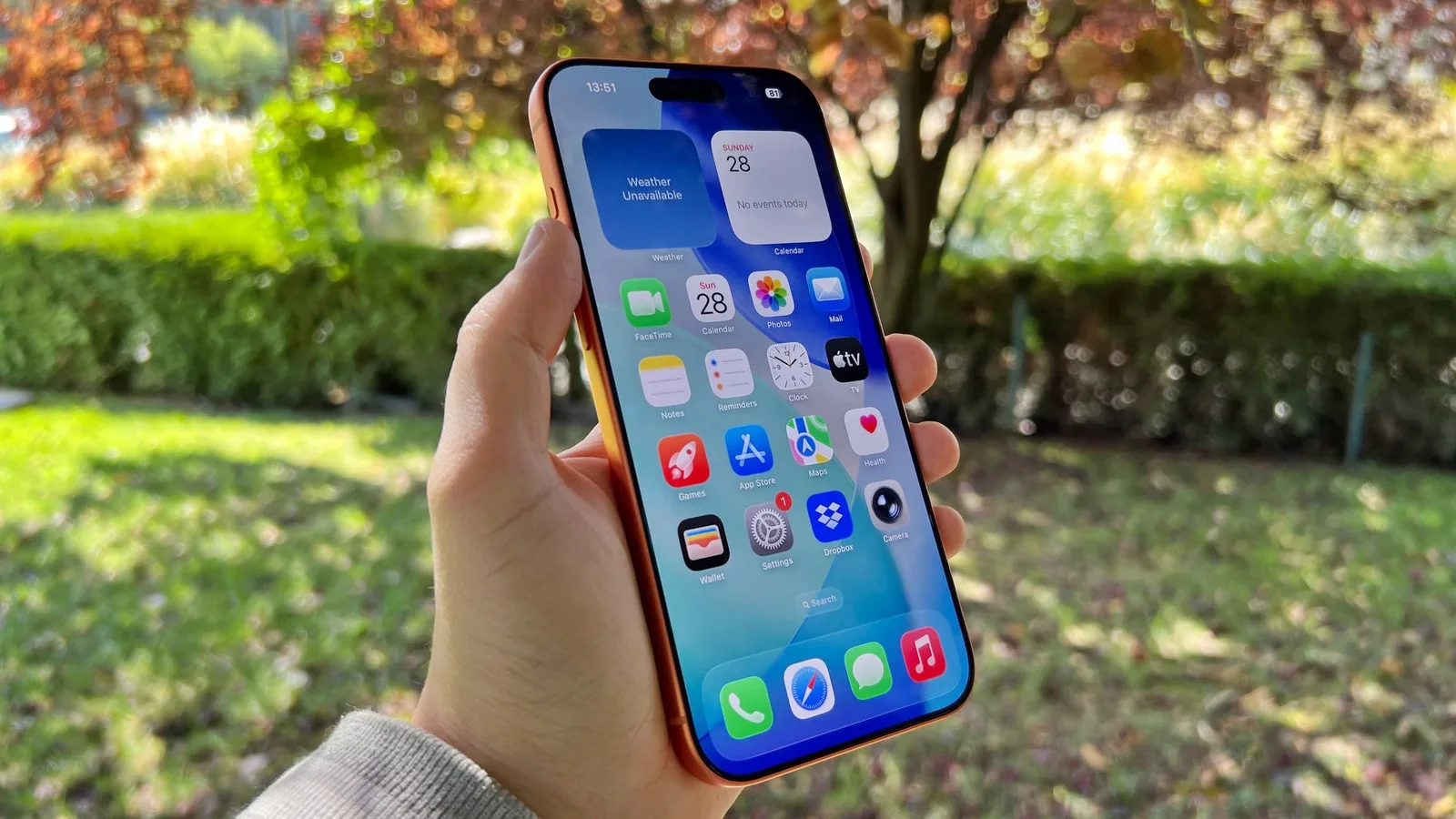 Un iPhone cu ecranul deschis, în natură, cu aplicații vizibile.