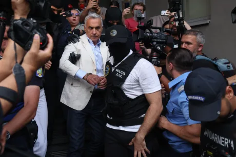 Călin Georgescu escortat de poliție după reținere pentru înșelăciune.