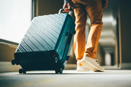 Călător cu valiză pe un coridor, pregătit pentru o nouă aventură.