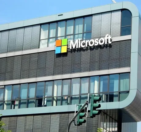 Clădirea Microsoft cu logo-ul companiei pe fațadă, sub un cer senin.