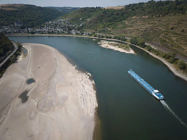 Râul cu nivel scăzut de apă și o barjă navigând pe el.