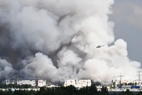Fum dens se ridică deasupra unui peisaj industrial afectat de atacuri aeriene.