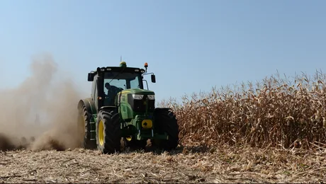 Tractor lucrând pe câmp, pregătind terenul pentru subvenții agricole.