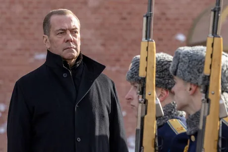 Dmitri Medvedev observând soldați în uniformă, cu o expresie serioasă.