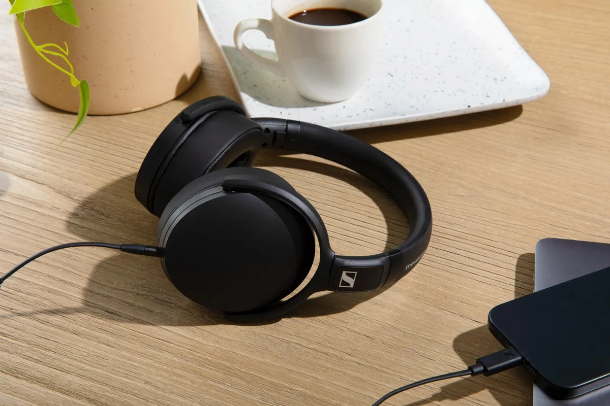 Căști Sennheiser pe birou lângă o cană de cafea.