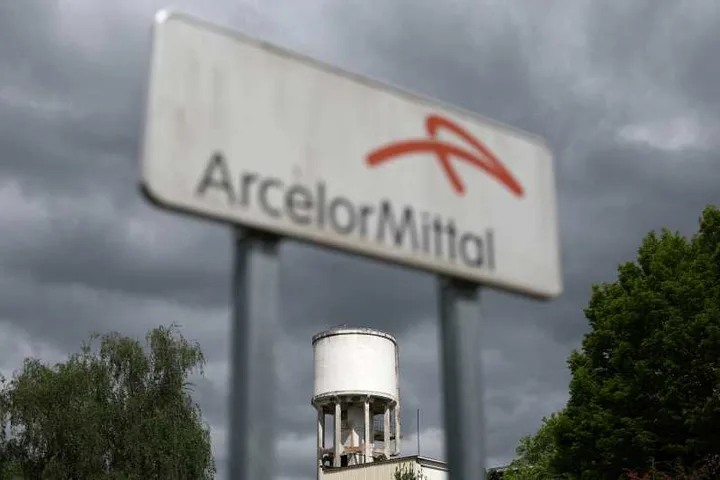 Semn ArcelorMittal pe fundalul unui cer întunecat, simbolizând dificultăți.