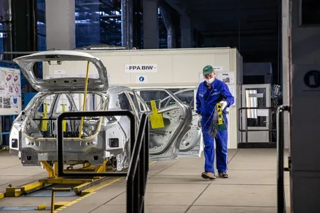 Un muncitor în fabrică, pregătind componente auto pentru asamblare.