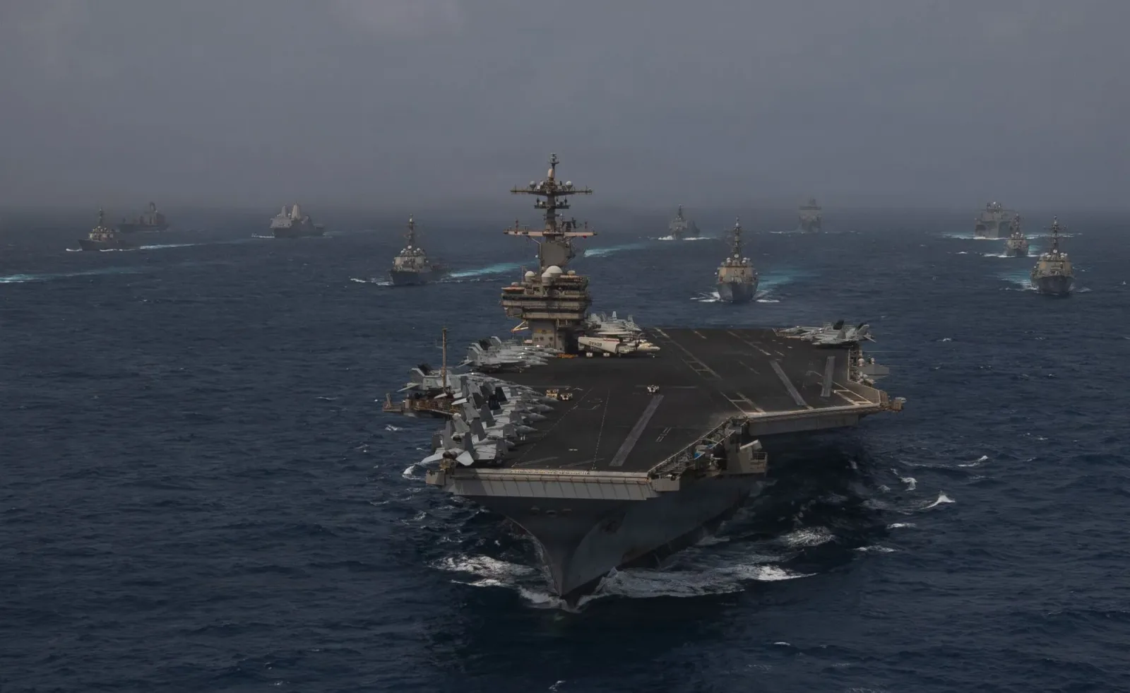 Nave militare în acțiune pe marea agitată, simbolizând tensiuni internaționale.