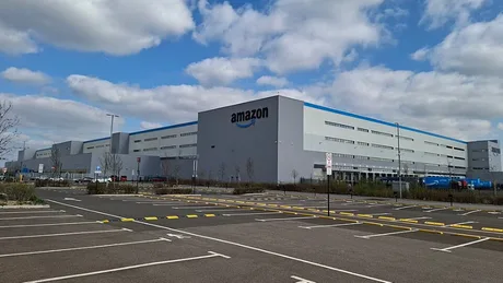 Centru de distribuție Amazon cu cer senin și parcări goale.
