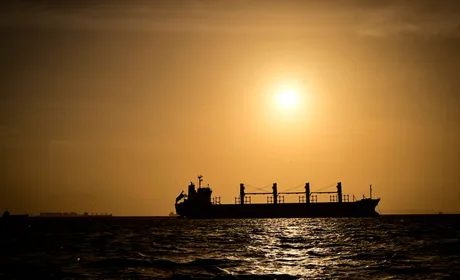 O navă cargo navighează pe un fundal de apus, simbolizând creșterea costurilor de tranzit.