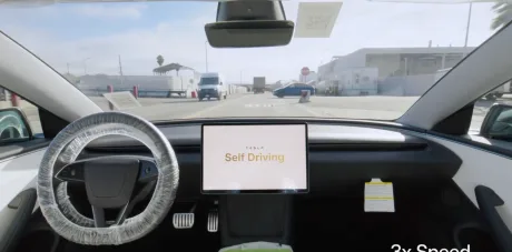 Interiorul unei mașini Tesla cu ecranul de control activat pentru conducere asistată.