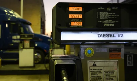 Pompa de motorină la o stație de alimentare, cu prețuri afișate.