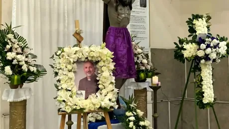 Aranjament floral în memoria preotului decedat, cu o fotografie și cruci decorate.