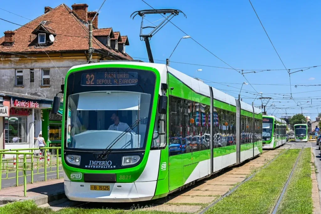 Tramvai STB pe o stradă din București, însoțit de clădiri istorice.