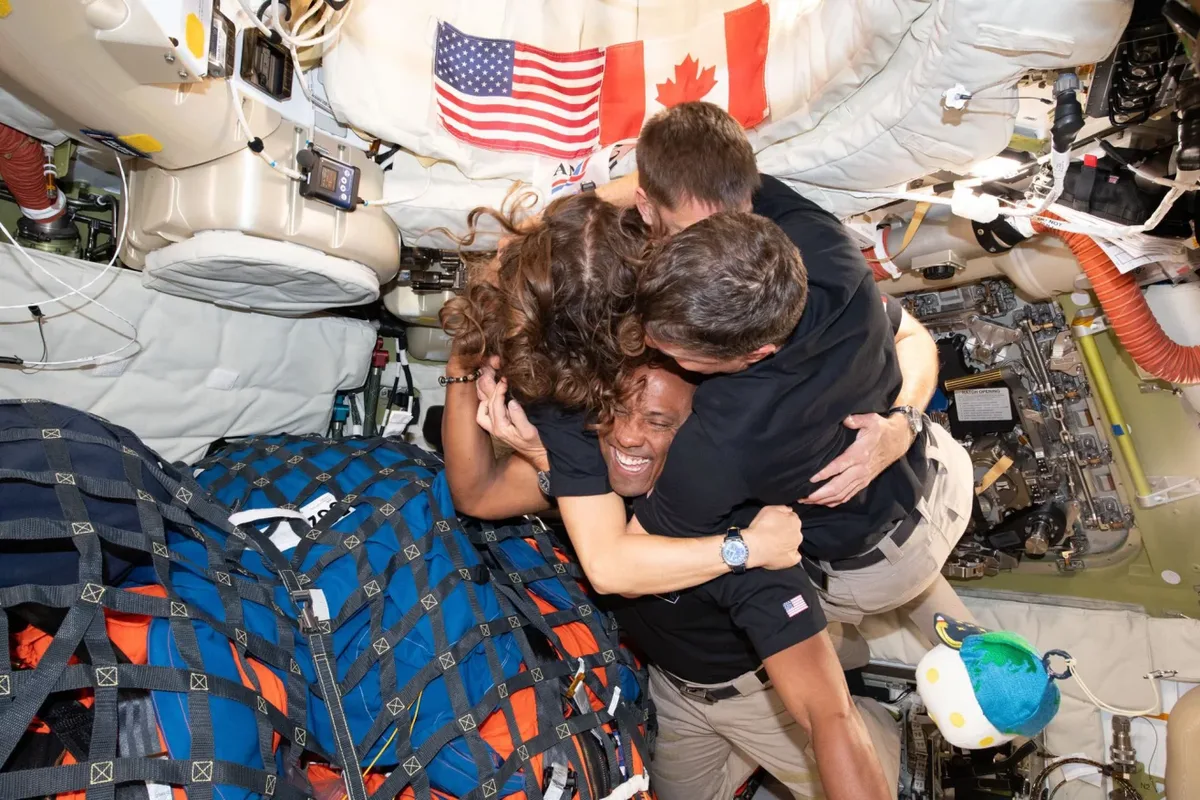 Astronauții se îmbrățișează în interiorul capsulei Orion.