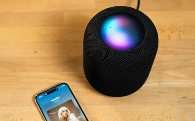 Dispozitiv inteligent Apple pe un birou, cu ecran colorat și smartphone alături.
