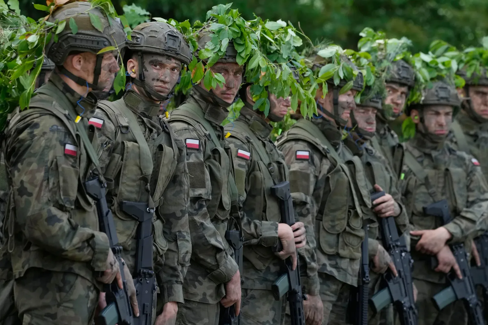 Soldați polonezi în uniformă, cu frunze pe cap, pregătiți de acțiune.
