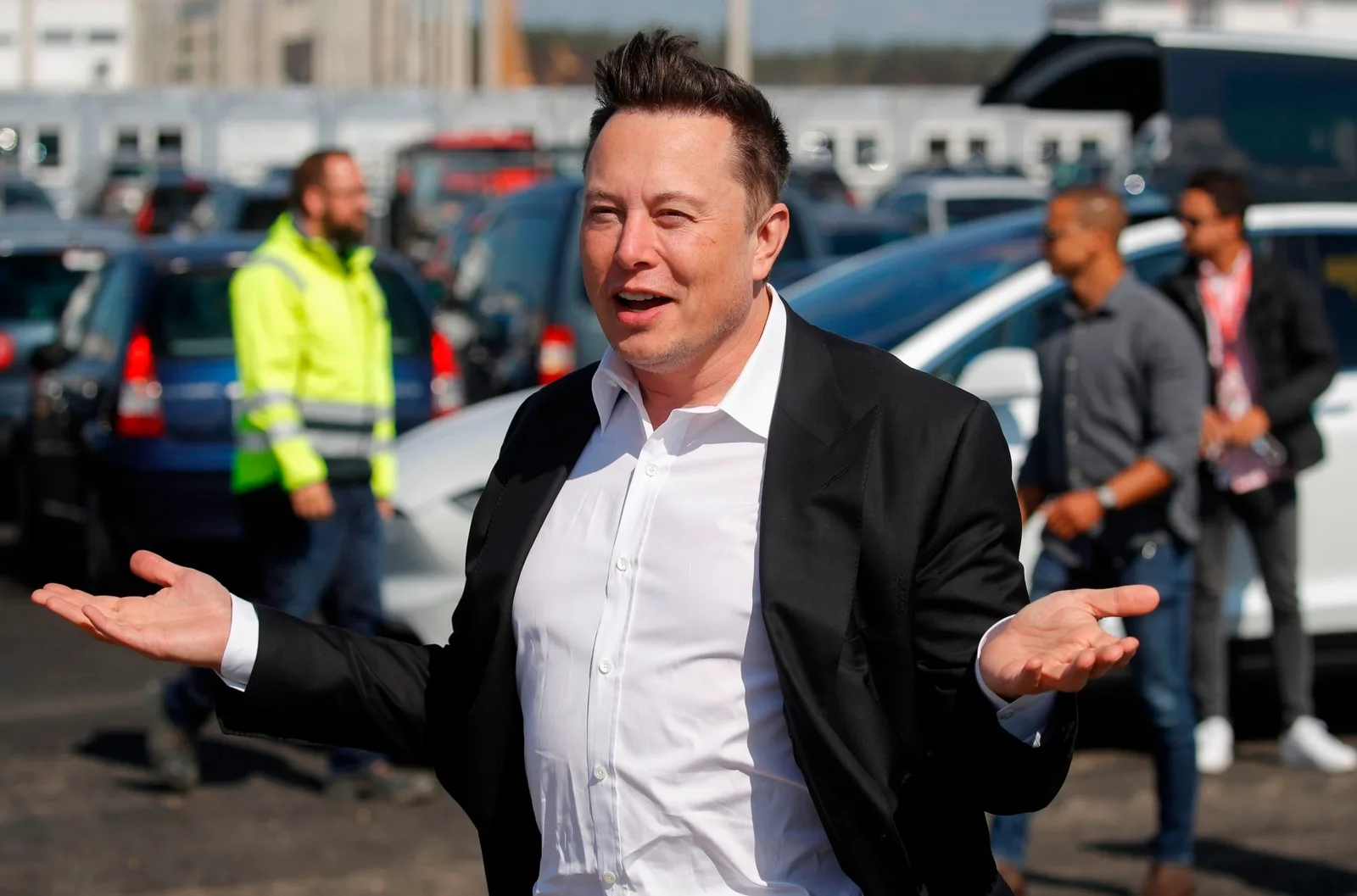 Elon Musk zâmbind și gesticulând într-un mediu urban.