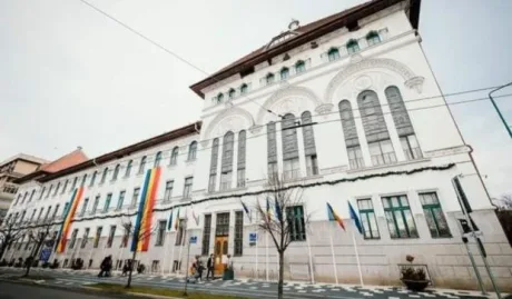 Clădirea Primăriei Timișoara, cu steaguri și arbori în față.