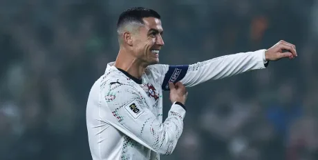 Cristiano Ronaldo zâmbind și arătând emblema echipei sale.