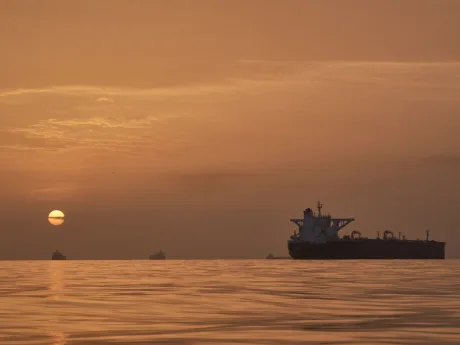 Apus de soare peste o navă pe mare, simbolizând tensiuni internaționale.