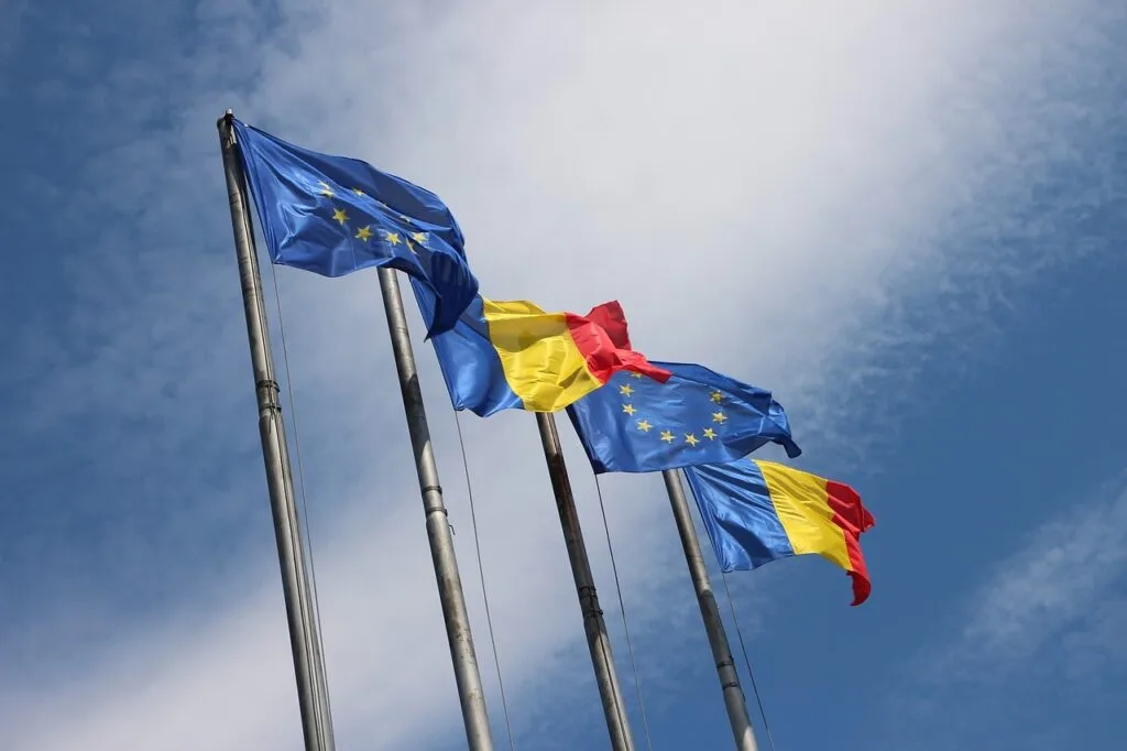 Steagurile României și Uniunii Europene fluturând în vânt.