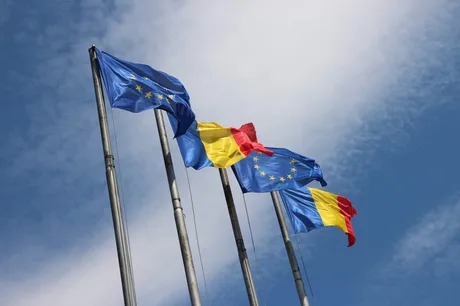 Steagurile României și Uniunii Europene fluturând în vânt.