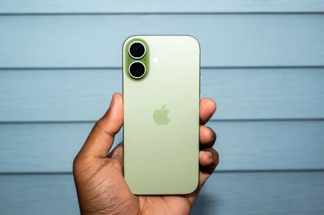 Un telefon iPhone verde, ținut în mână, pe un fundal albastru deschis.