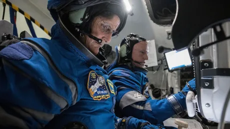 Astronauți în costume speciale, pregătiți pentru o misiune în spațiu.