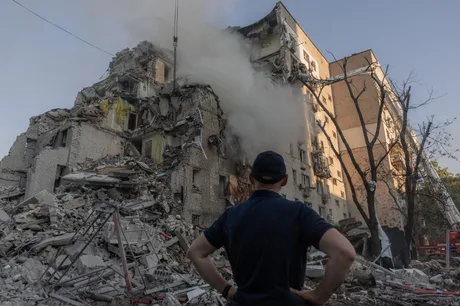 Clădire distrusă în urma atacurilor aeriene din Ucraina, cu fum ieșind din ruine.
