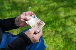 Bărbat cu bancnotă de 50 de euro pe iarbă verde.