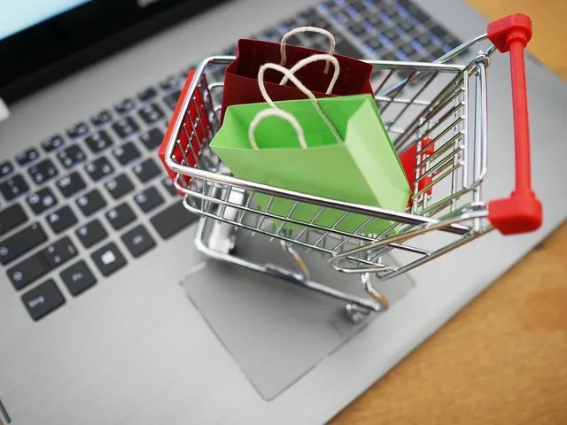 Cumpărături online cu un cărucior de supermarket pe un laptop.