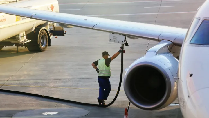Un angajat al aeroportului umple un avion cu combustibil.