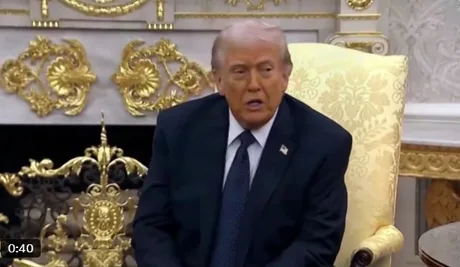 Donald Trump discutând în timpul unei întâlniri oficiale, cu un decor elegant în fundal.