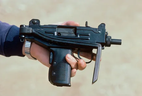 Un pistol mitralieră ținut în mână, pe un fundal neutru.