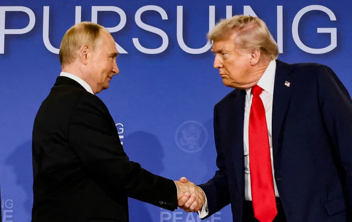 Donald Trump și Vladimir Putin strâng mâinile în cadrul unei întâlniri oficiale.