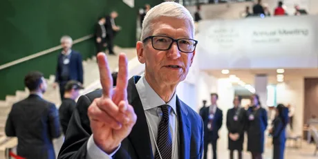 Tim Cook zâmbind și făcând semnul victoriei la un eveniment.
