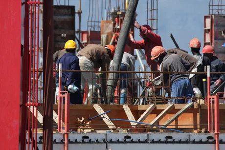 Muncitori pe un șantier de construcții, lucrând la o structură complexă.