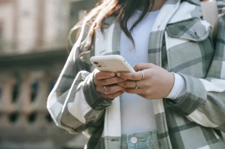 Utilizator verificând mesaje pe telefonul mobil în aer liber.