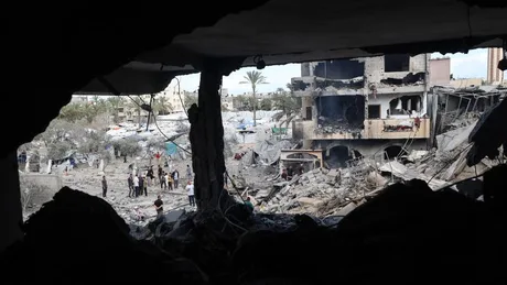 Peisaj distrus în Gaza, cu clădiri avariate și oameni adunați.