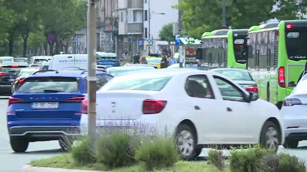 Trafic urban cu mașini diverse pe o stradă aglomerată.