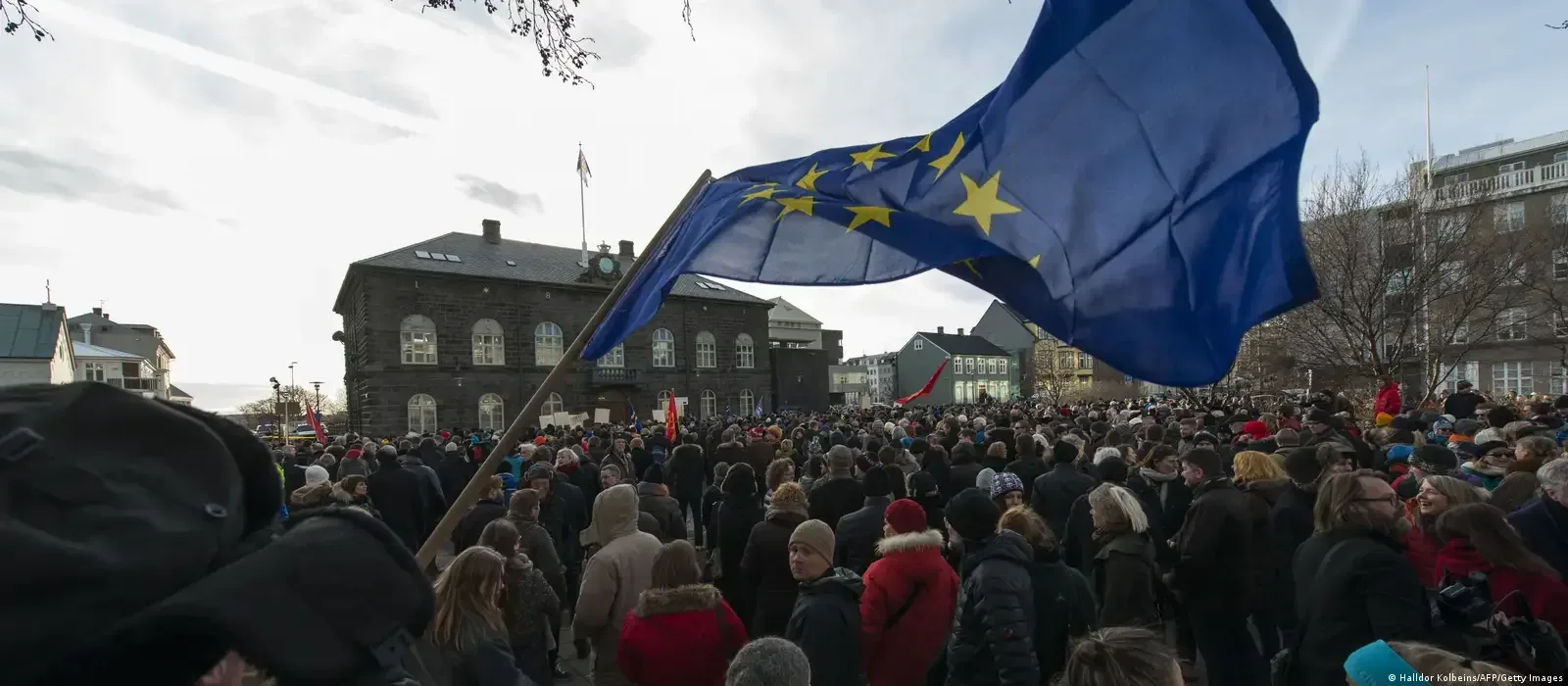 O mulțime de oameni protestează cu steagul Uniunii Europene.
